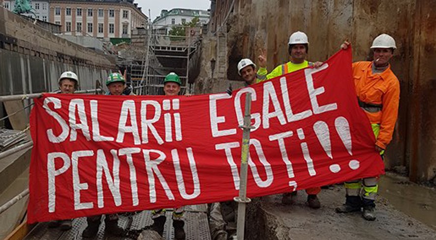Rumænske metroarbejdere med banner der kræver ligeløn for alle - skrevet på rumænsk