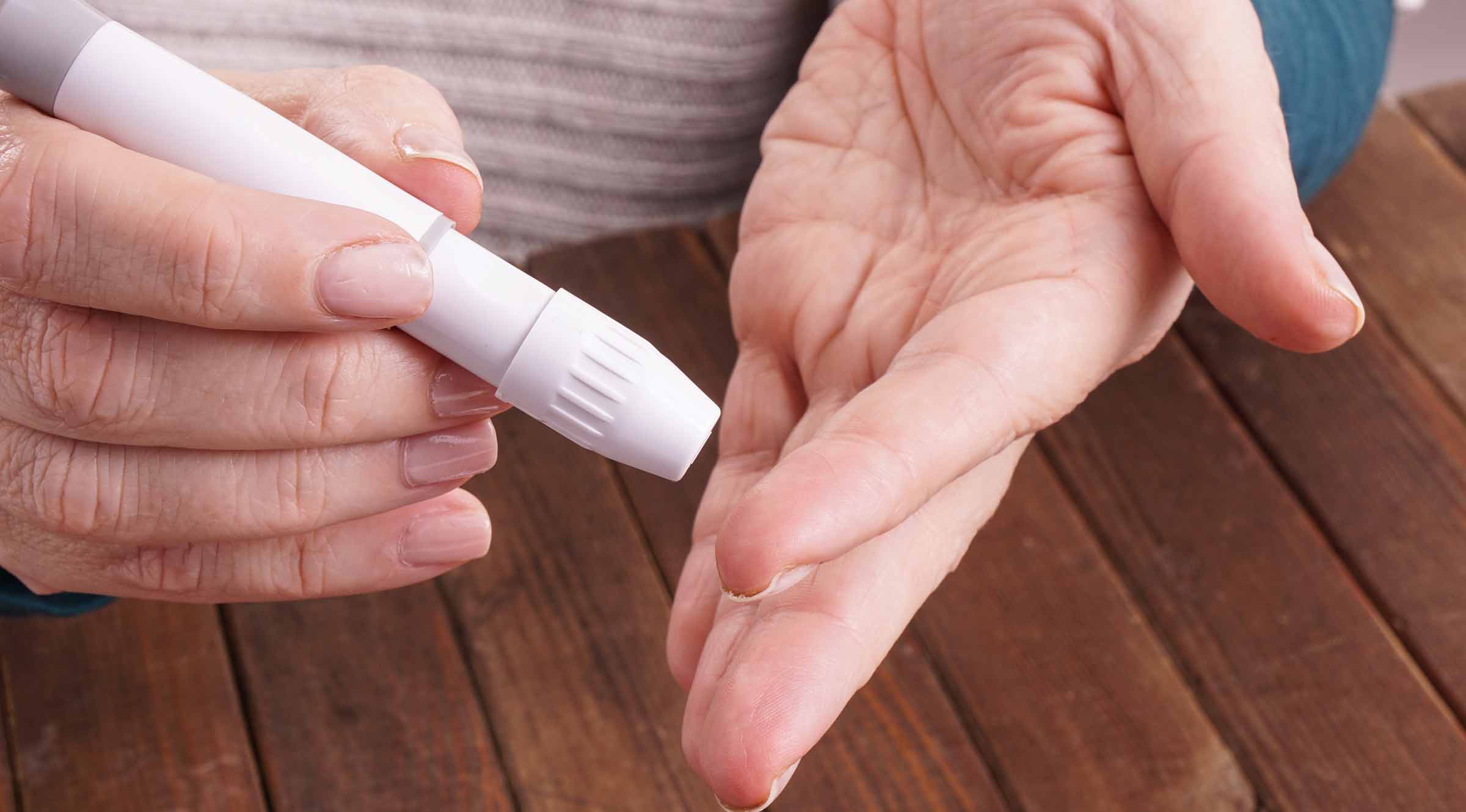 Person stikker sig i fingerne for at måle sit blodsukker